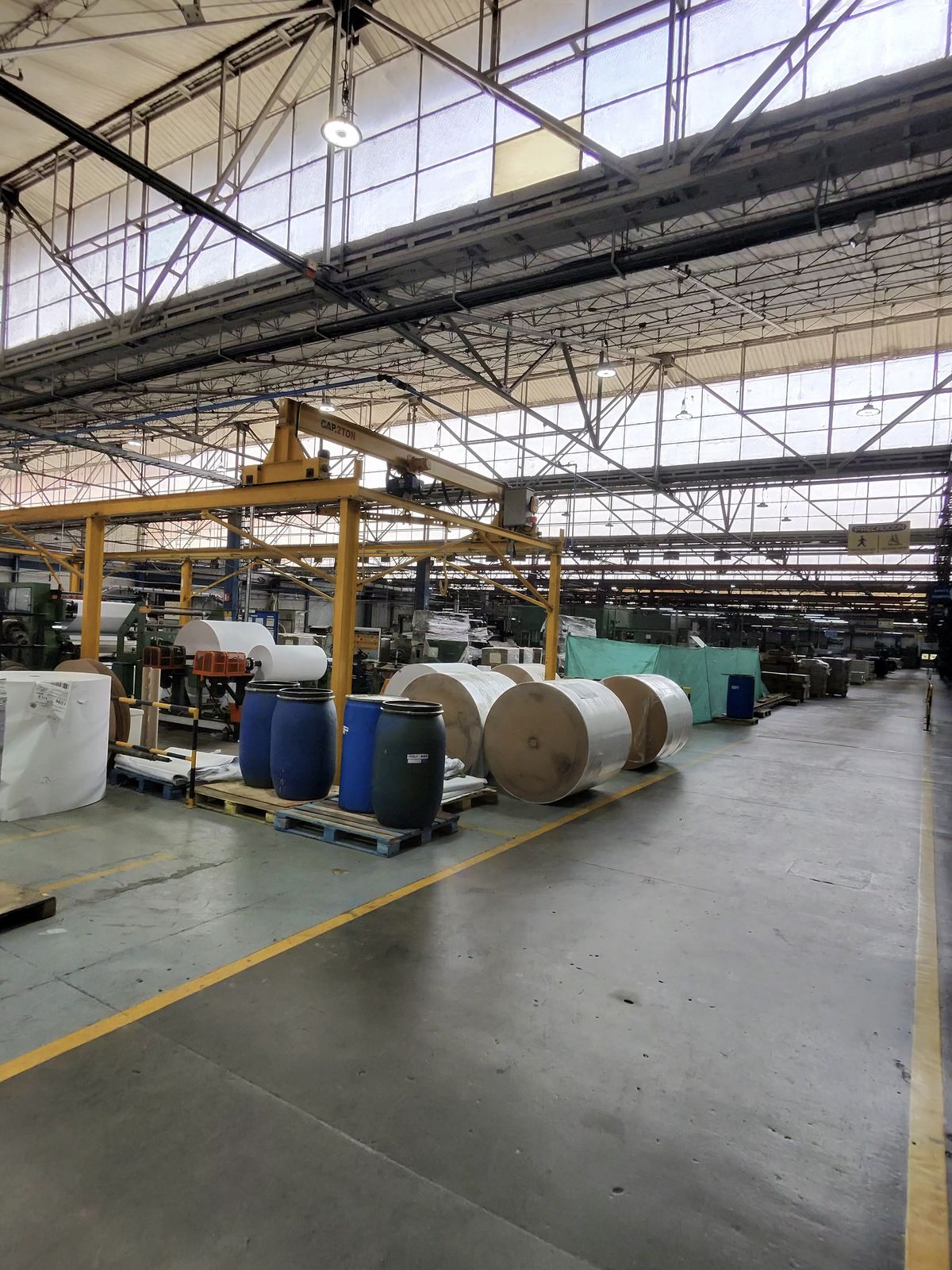 Paper mill finishing hall with large white and kraft reels on the floor